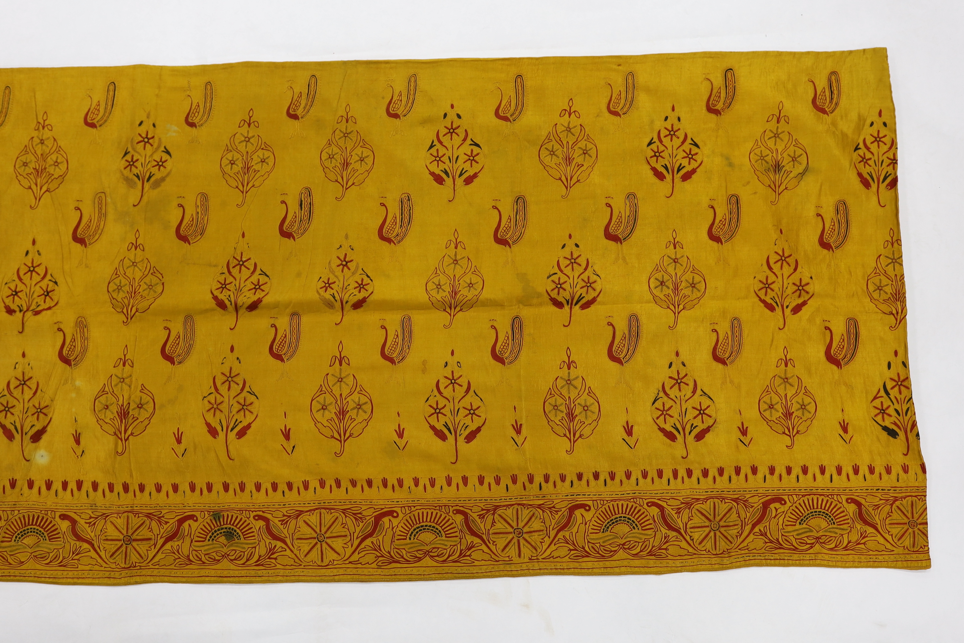 A 19th century fine cream woven Kashmiri shawl with blue and red teardrop design borders, an early 20th century gold satin pelmet with spot motifs of peacocks and flowers, 204cm long x 71cm high and a length of silk with